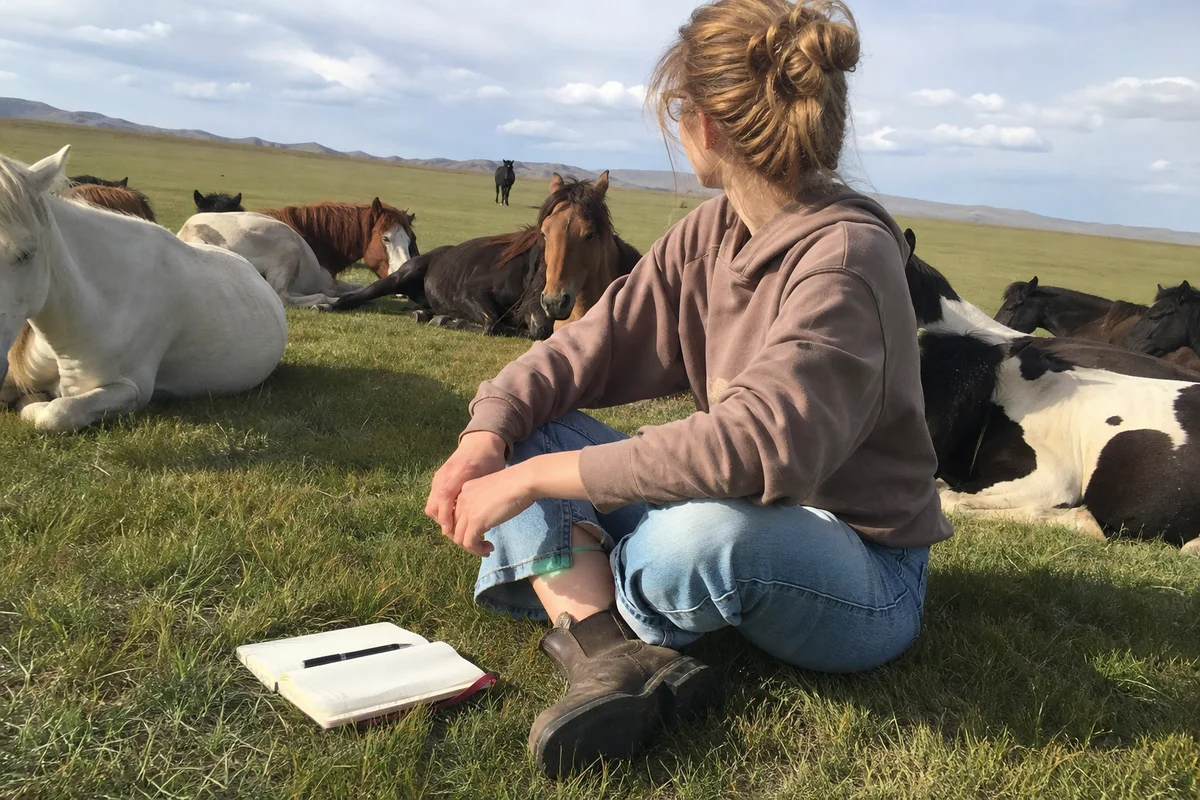 Guest sitting among the resting herd in afternoon light, journal beside them